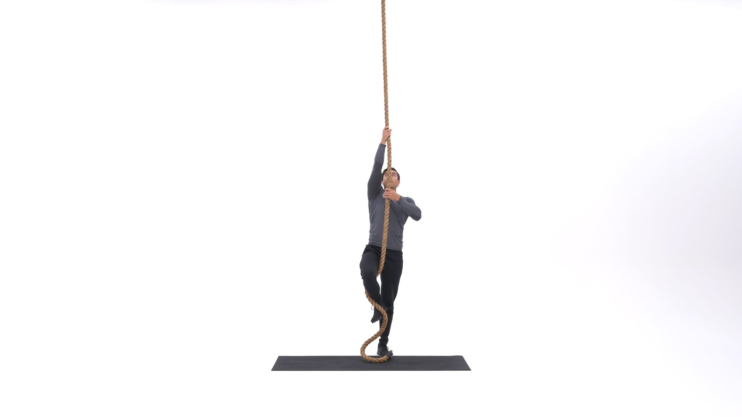 فرد در حال آویزان شدن از طناب، با دستانی کشیده و بدن در حالت آماده‌باش برای شروع حرکت است.
