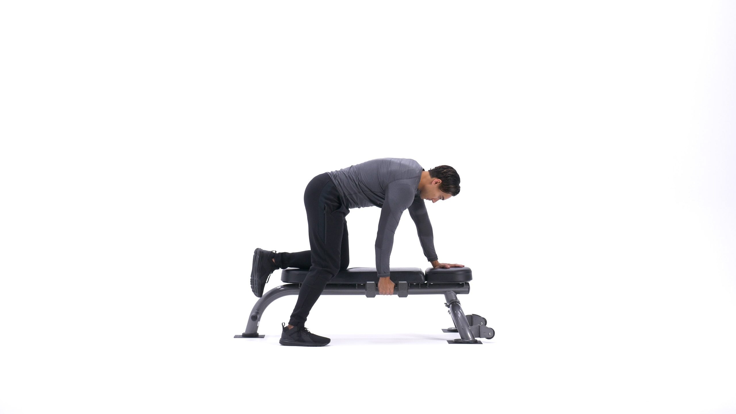 شروع حرکت زیربغل دمبل تک خم، فرد با یک دست به نیمکت تکیه داده و دمبل را در دست دیگر در حالت کشش کامل نگه داشته است.